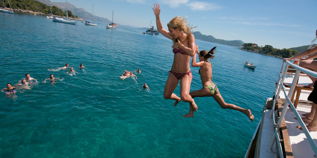 Summer sailing friends jumping ocean